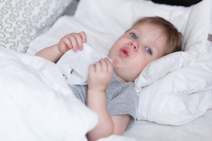 Little kid boy with sore throat cough in the bed close-up
