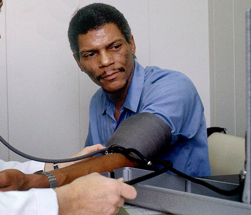 Black man getting his blood pressure taken to check for hypertension, a sign of cardiovascular disease, with a blood pressure cuff