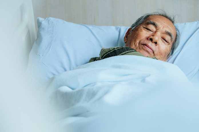 Portrait Of Senior Man Lying Down On Bed At Hospital