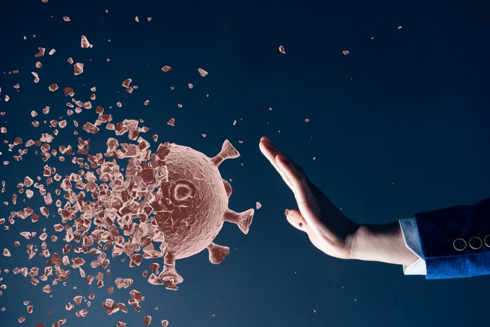 illustration of coronavirus particle coming towards a human hand blocking the way