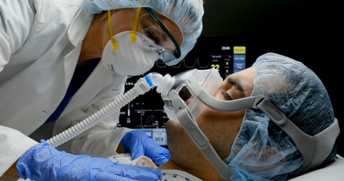 Female doctor checking on Covid-19 infected patient while connected to a ventilator