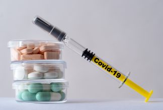 Syringe with covid-19 coronavirus vaccine and medication tablets for symptoms.