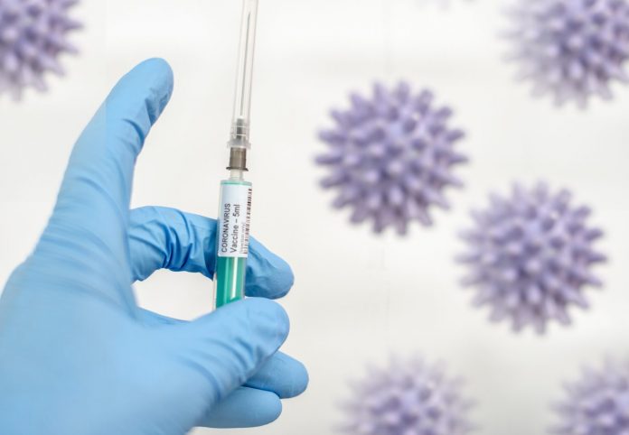 Gloved hand holding COVID-19 vaccine in syringe on a background of SARS-CoV-2 particles to represent preventive effect against diabetes and other health issues
