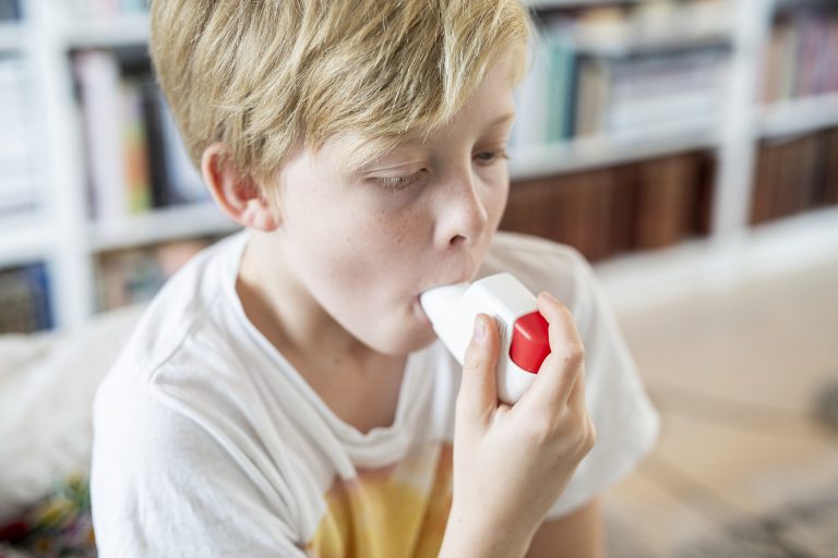 Boy using inhaler to illustrate allergic diseases of childhood