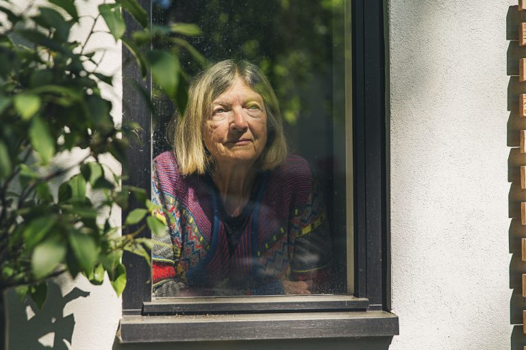 Senior lady looking through window