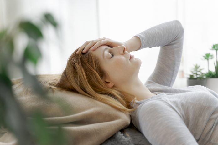 Woman lying down suffering from symptoms of long covid