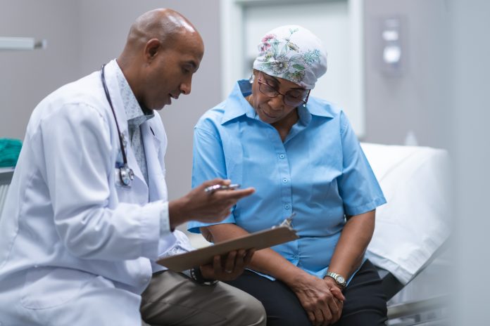 doctor conducts geriatric assessment with older cancer patient.