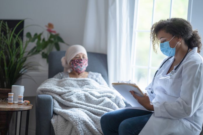 Senior asian female cancer patient wearing mask talking to doctor