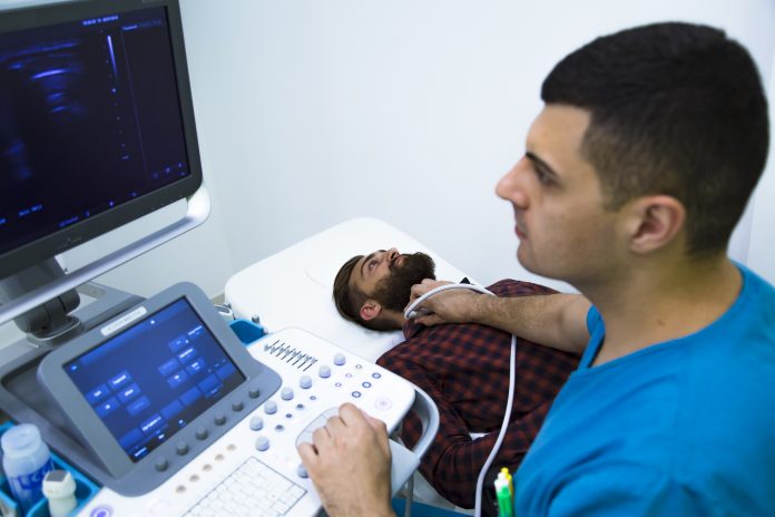 Doctor examining thyroid gland with ultrasound machine in hospital