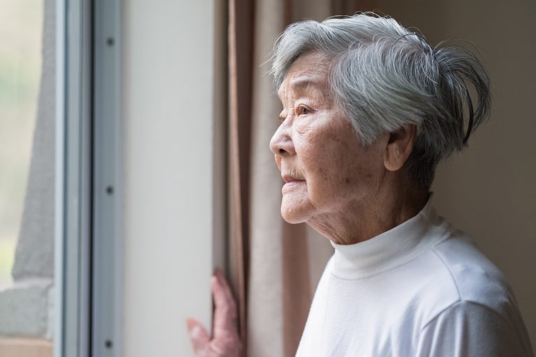 Serious Asian Senior Woman in 90s Looking Out of Window