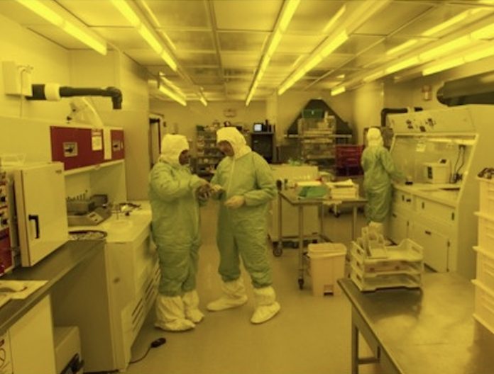 Lab workers in protective suits in a lab at the Kansas Center of BioModular Multi-Scale Systems for Precision Medicine making lab-on-a-chip devices.