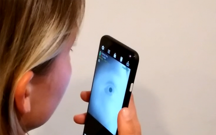 Woman with blond hair scans pupil with smartphone app to search for neurological diseases