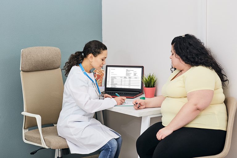 Nutritionist calculating body mass index of woman for obesity treatment in a clinic room.