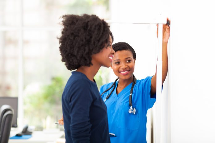170546605 african nurse measuring patient's height