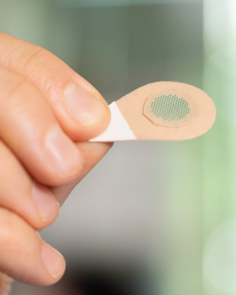 A magnified view of a microneedle patch with green tattoo ink.