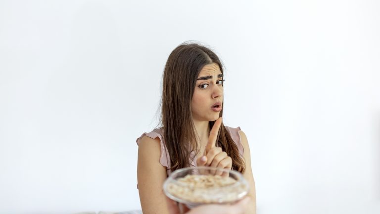 Cropped shot of a young girl refuses to eat peanuts isolated on the white background.