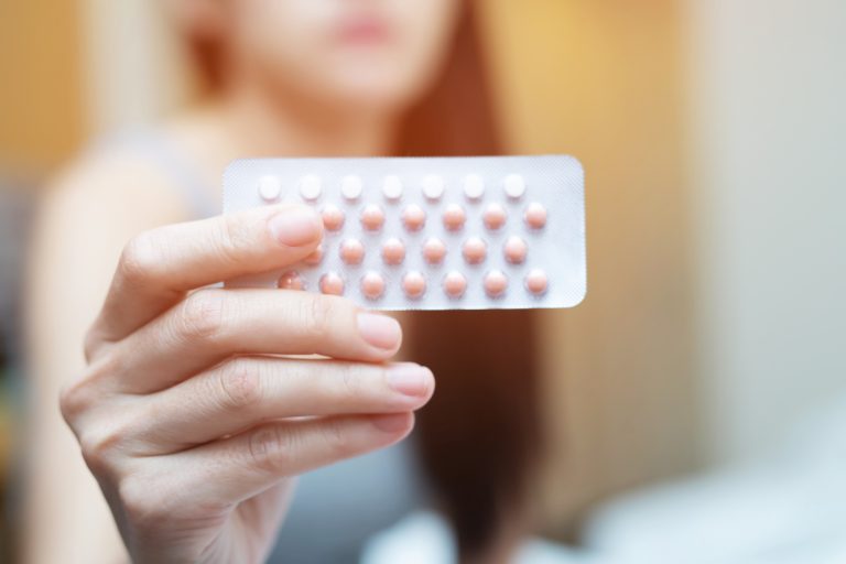 Woman holding birth control pills in hand to illustrate to impact of estrogen exposure on stroke risk after the menopause