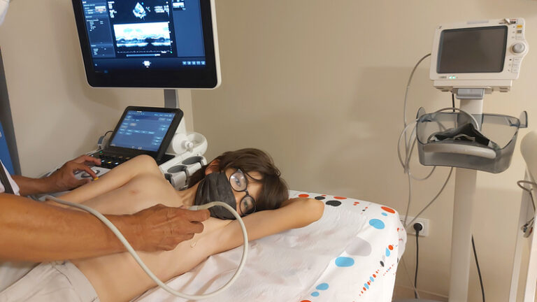 Doctor completing an echocardiogram on a young male patient's heart by using ultrasound equipment to look for signs of rheumatic heart disease.