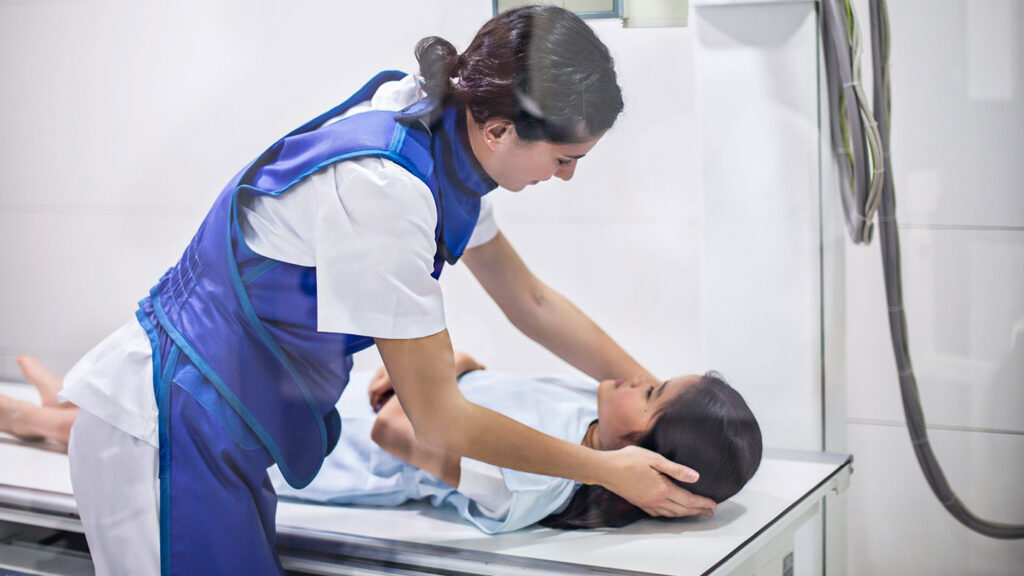 Nurse preparing child patient for an x-ray at hospital