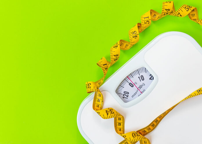1611218697 Weight loss control planning. White scale and measuring tape for body dieting healthy life. Green background. Top view copy space for banner